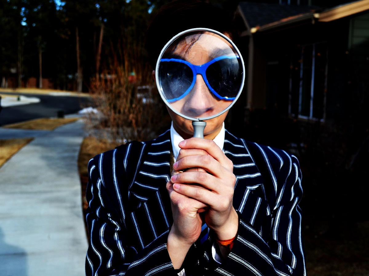 Stylish designer looking through magnifying glass